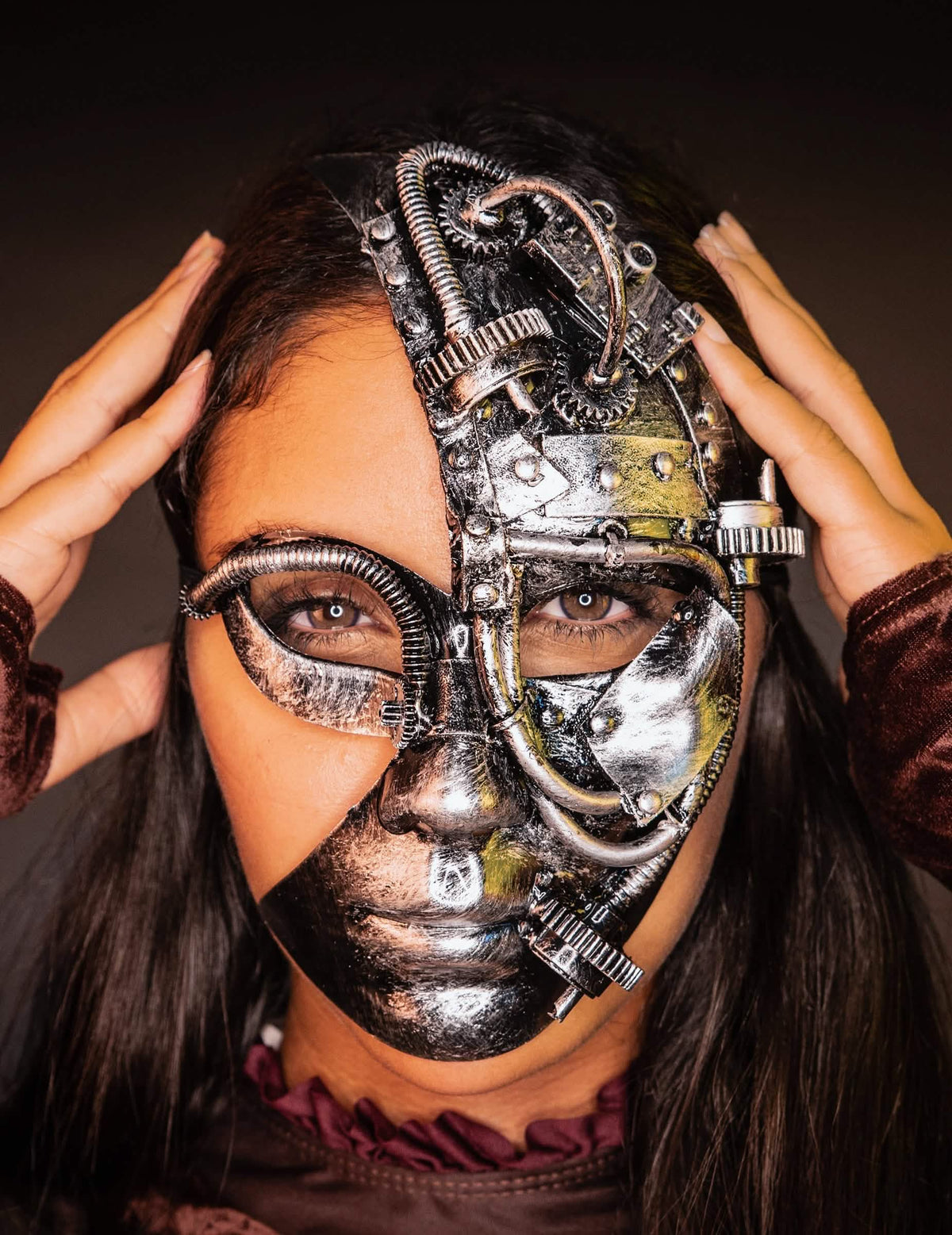 Vista frontal com as mãos nas têmporas da meia máscara robot steampunk