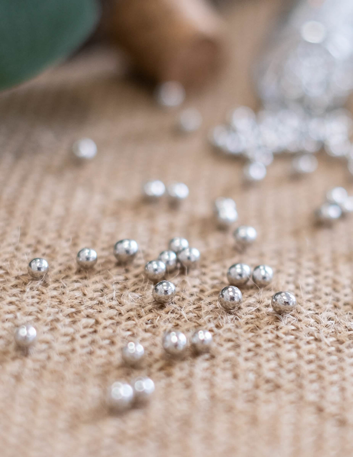 Detalhe das esferas prateadas em serapilheira dos confeitos de pérolas de casamento para festa
