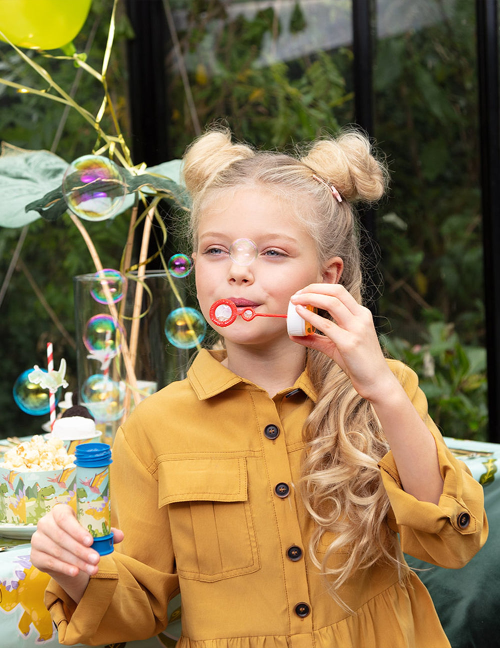 Enfant soufflant des bulles du flacon bulles de savon Dino Party