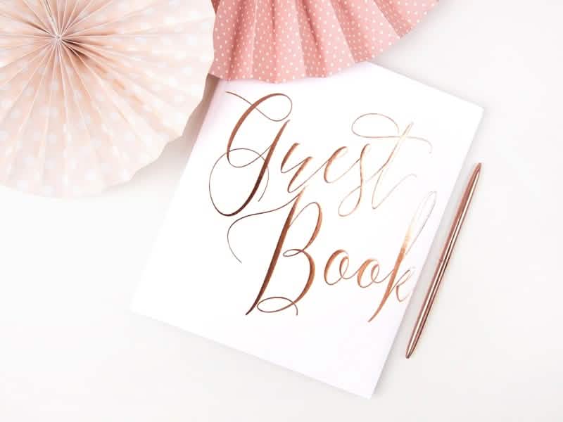 Encenação com caneta e rosetas do livro de visitas para casamento branco e ouro rosa