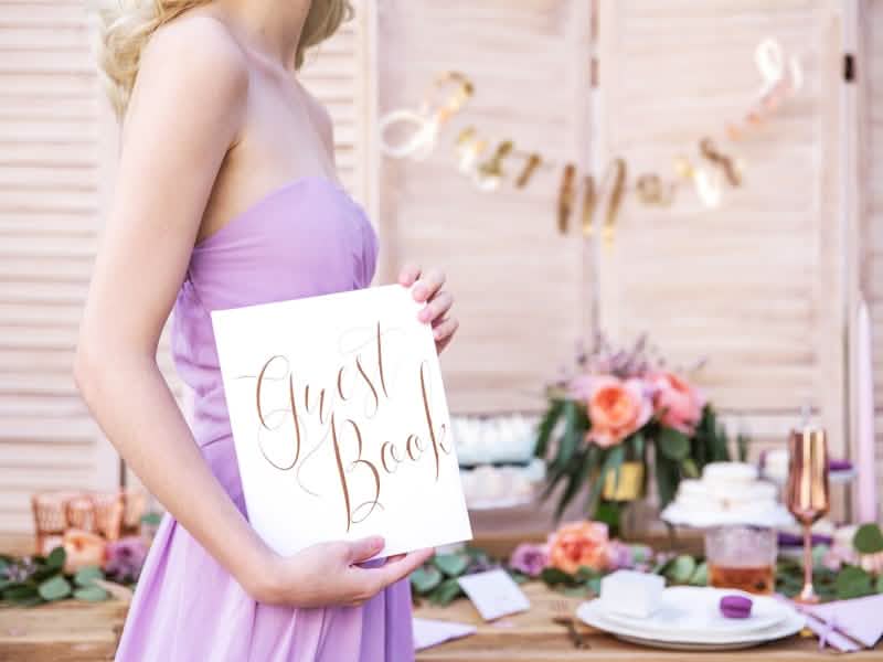 Encenação com o livro de visitas na mão para casamento branco e ouro rosa