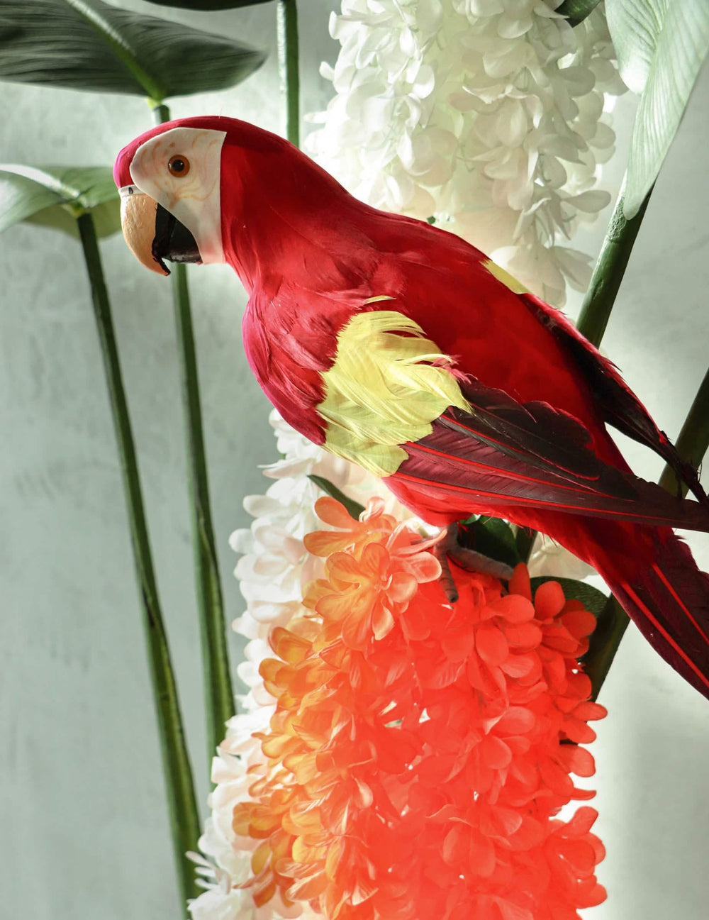 Detalhe do papagaio vermelho decorativo na grinalda de flores de orquídea para casamento