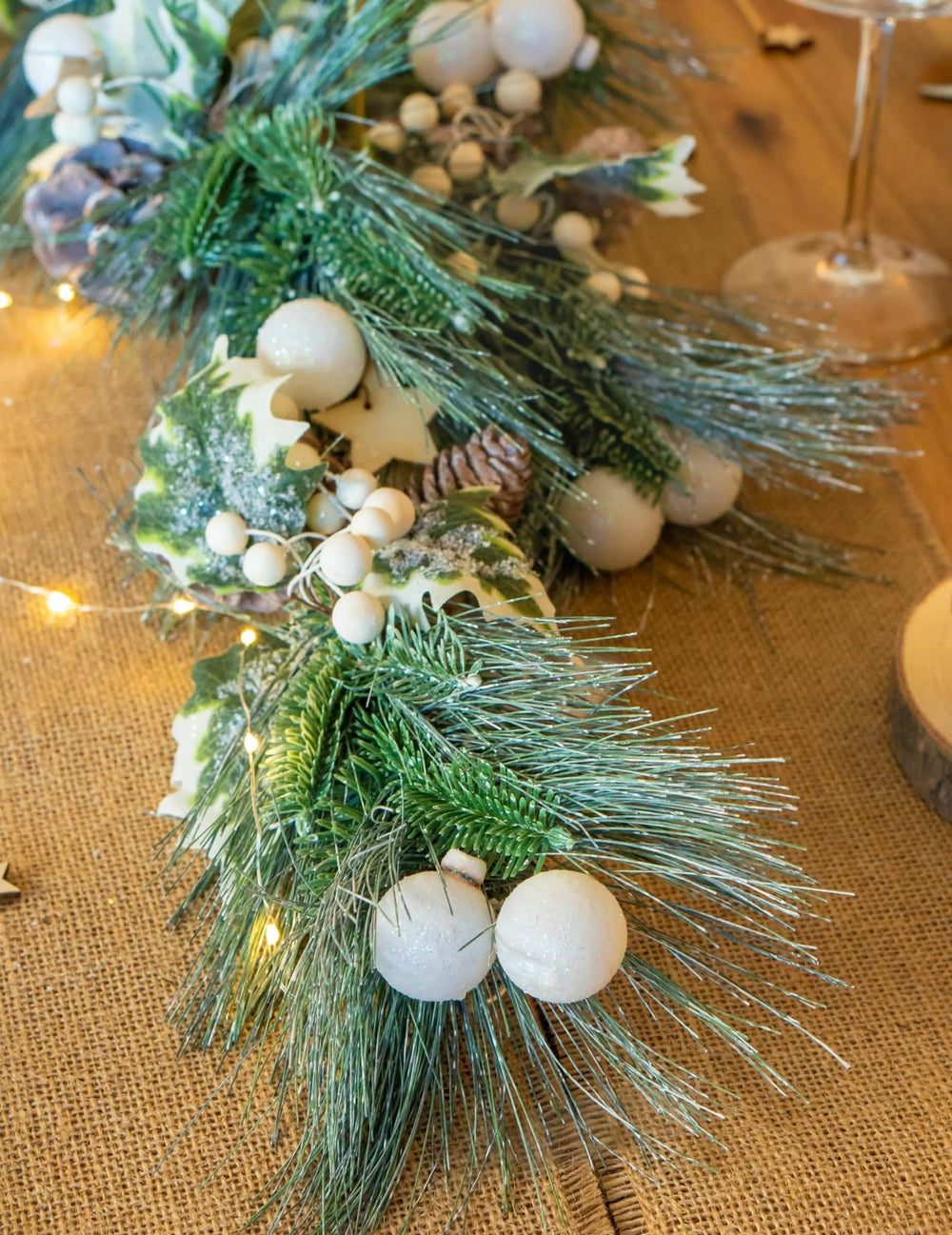 Detalhe das agulhas de pinheiro e das bolas brancas da guirlanda de natal folhagem verde e pinhas