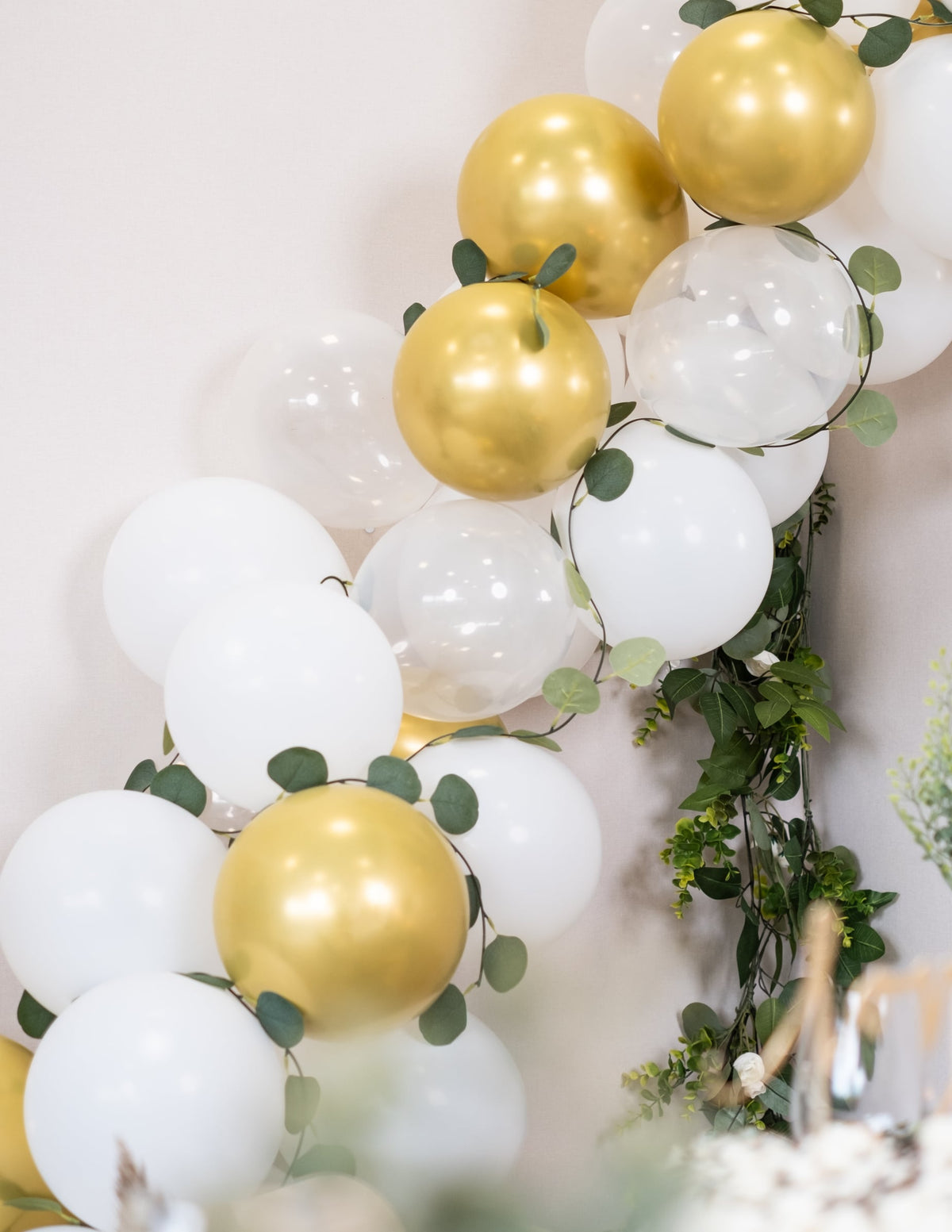 Gros plan sur la décoration végétale du kit arche de 60 ballons blanche et or avec eucalyptus végétale
