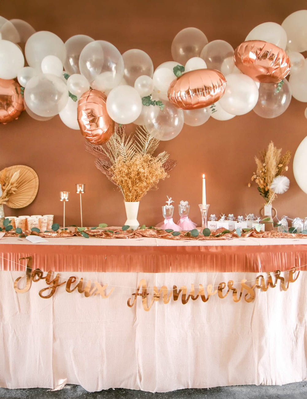 Encenação numa mesa de aniversário do kit arco de 70 balões ouro rosa com eucalipto e rosas