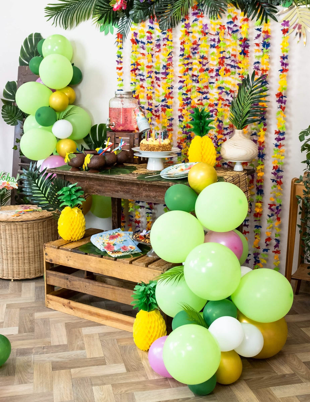 Ambiente festivo do buffet com o kit de arco de 70 balões tropical e folhas de selva