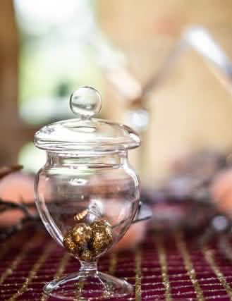 Grande plano das bolas douradas no interior da mini caixa de doces de vidro com pé