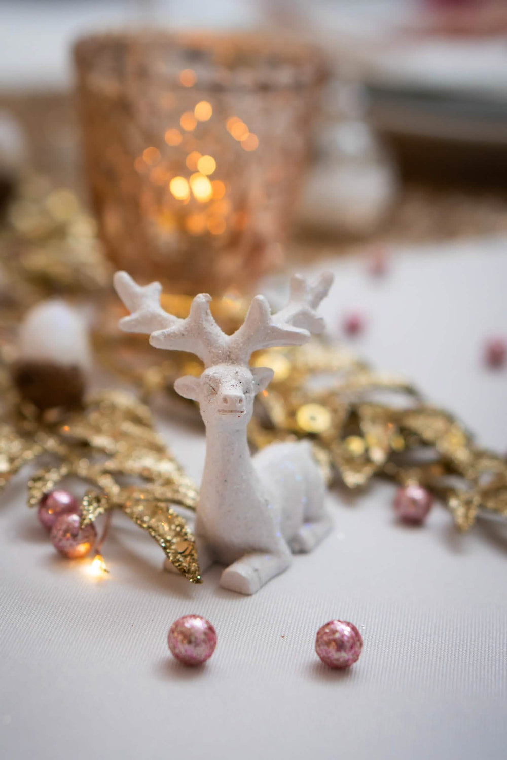 Detalhe da encenação com rena branca das mini bolas brilhantes para decoração ouro rosa