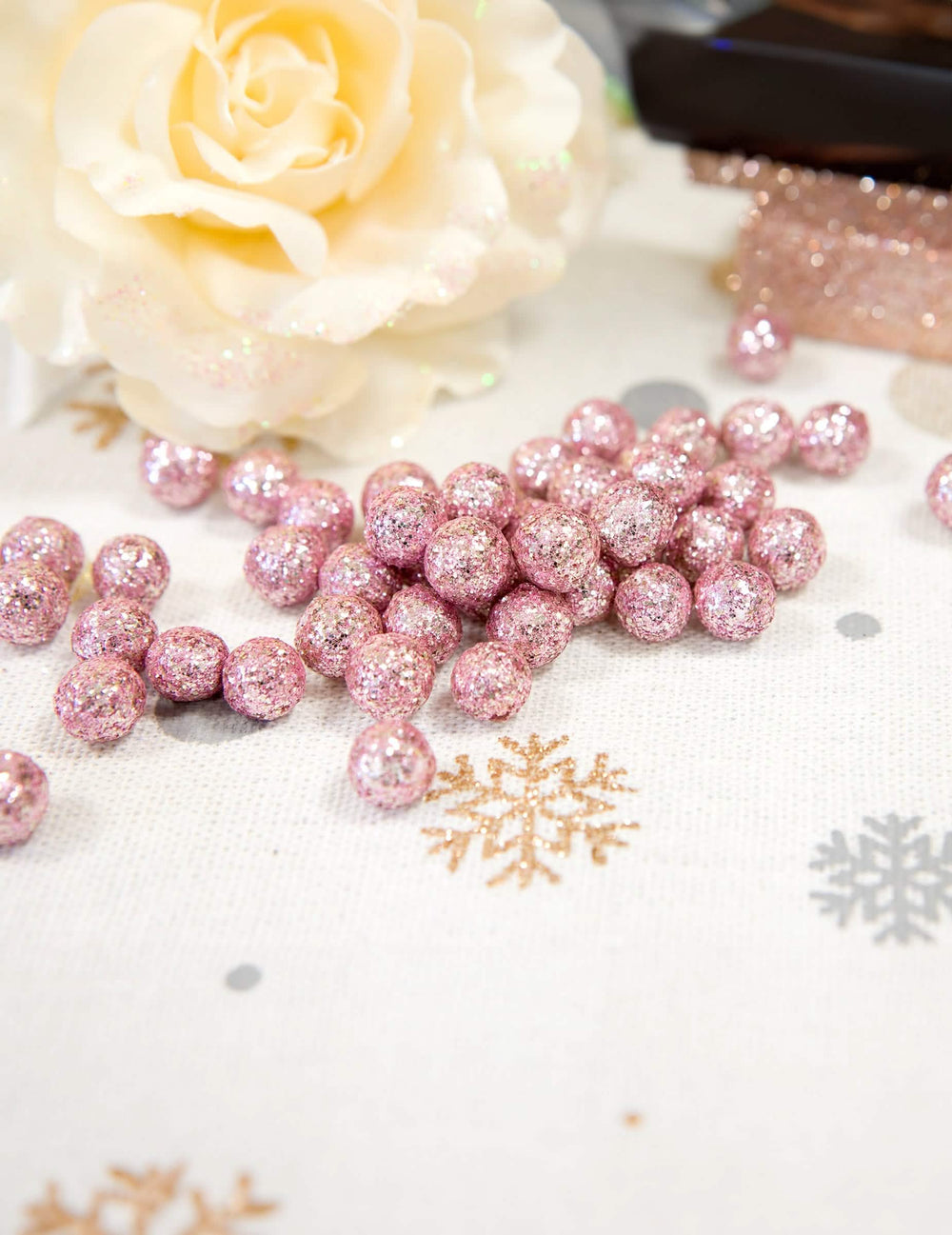 Detalhe da encenação com flor branca das mini bolas com brilhantes para decoração ouro rosa