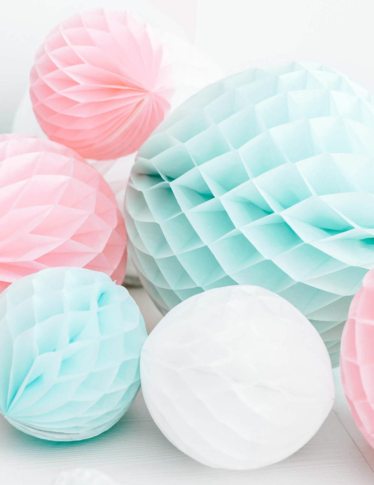 Mise em cena em tons pastel da bola de papel alveolado para decoração de festa branco
