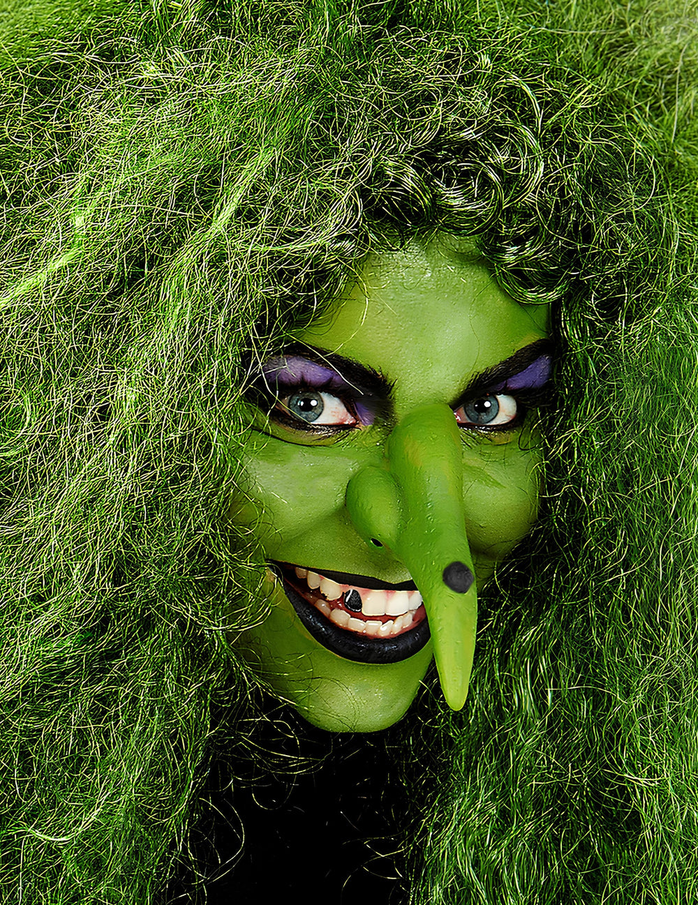 Gros plan sur le visage maquillé en sorcière du maquillage professionnel à l'eau pour visage et corps vert