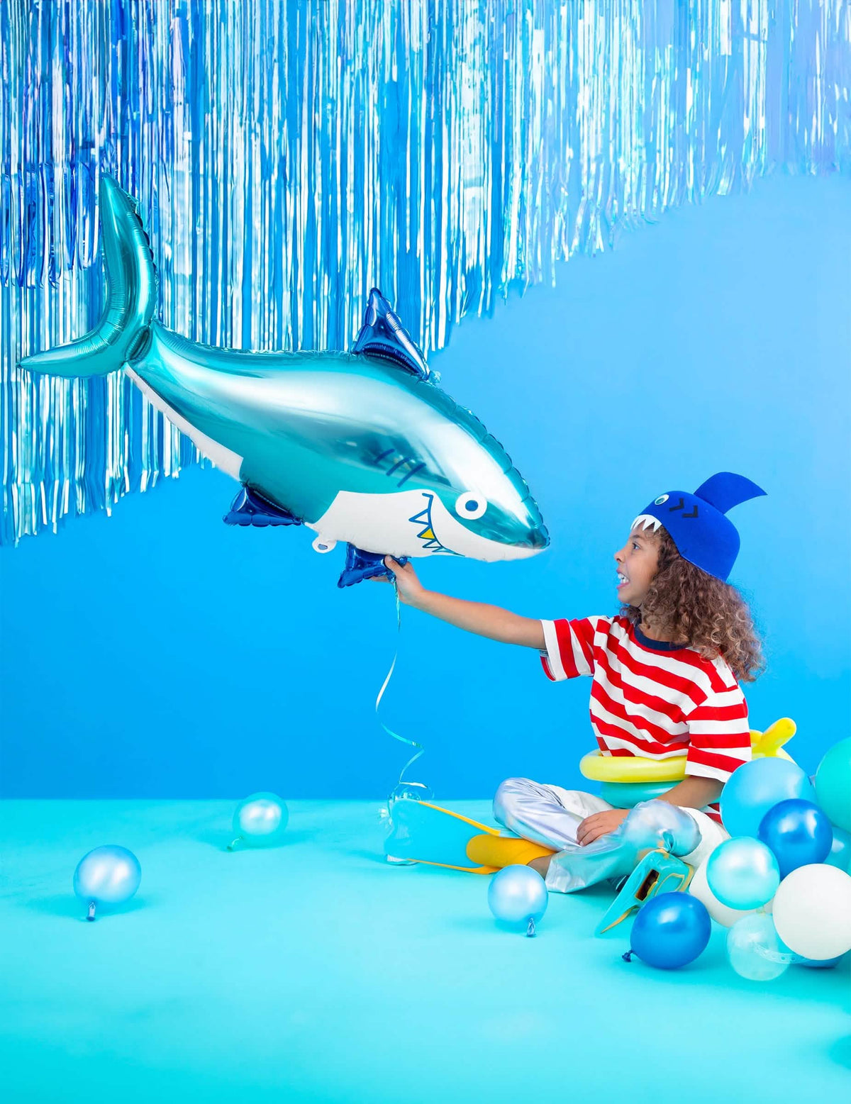 Decoração com um balão tubarão e uma cortina de fios metalizados para festa azul noite