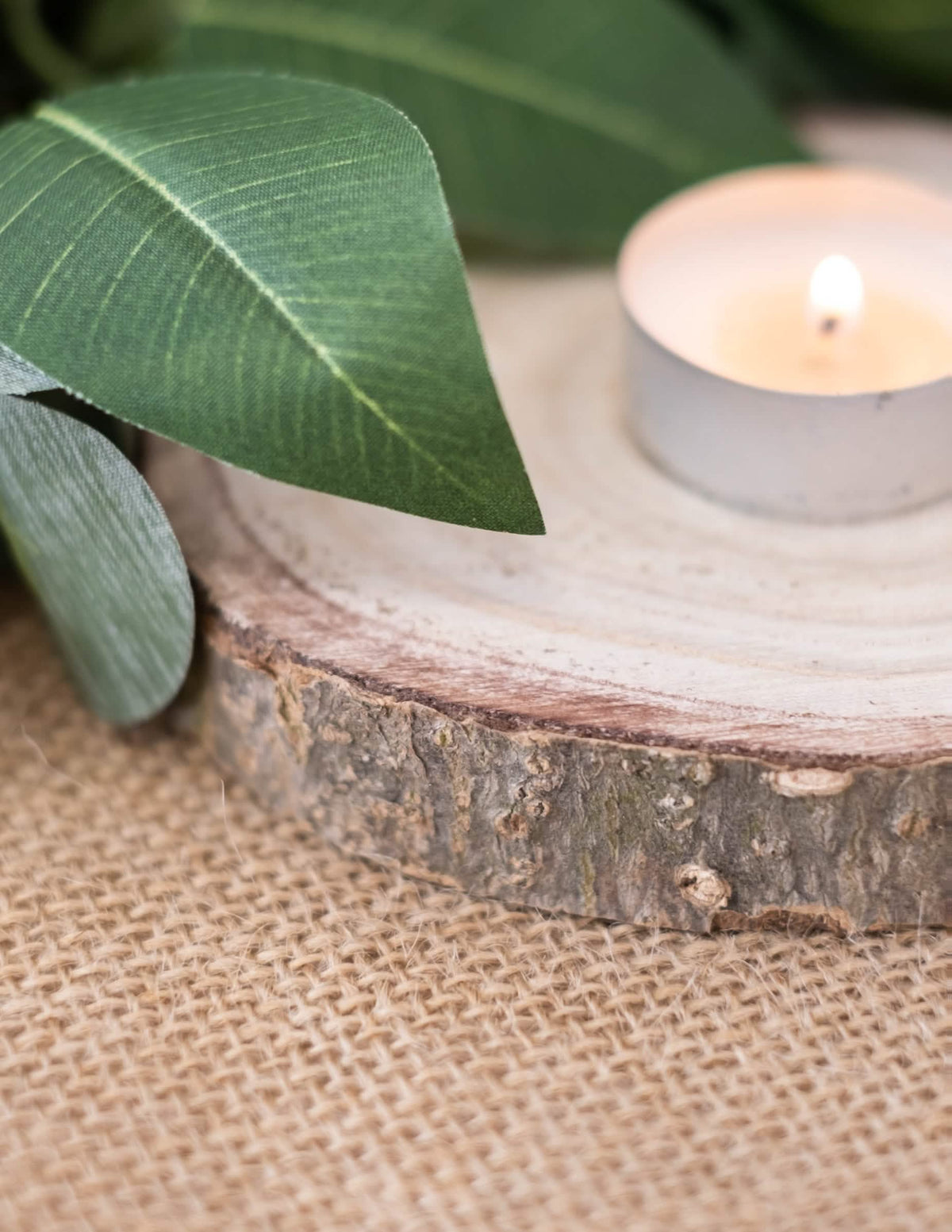 Detalhe da vela sobre o tronco de madeira natural para decoração de casamento