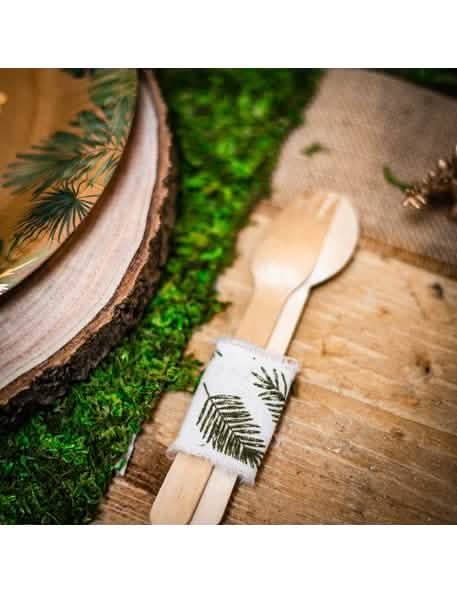 Em situação sobre talheres de fita de linho folhas tropicais