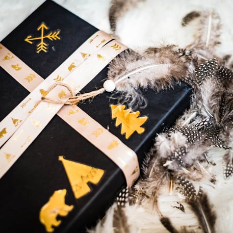 Mise en situation sur un emballage cadeau du ruban satin indian forest taupe floqué or motifs tipis et ours