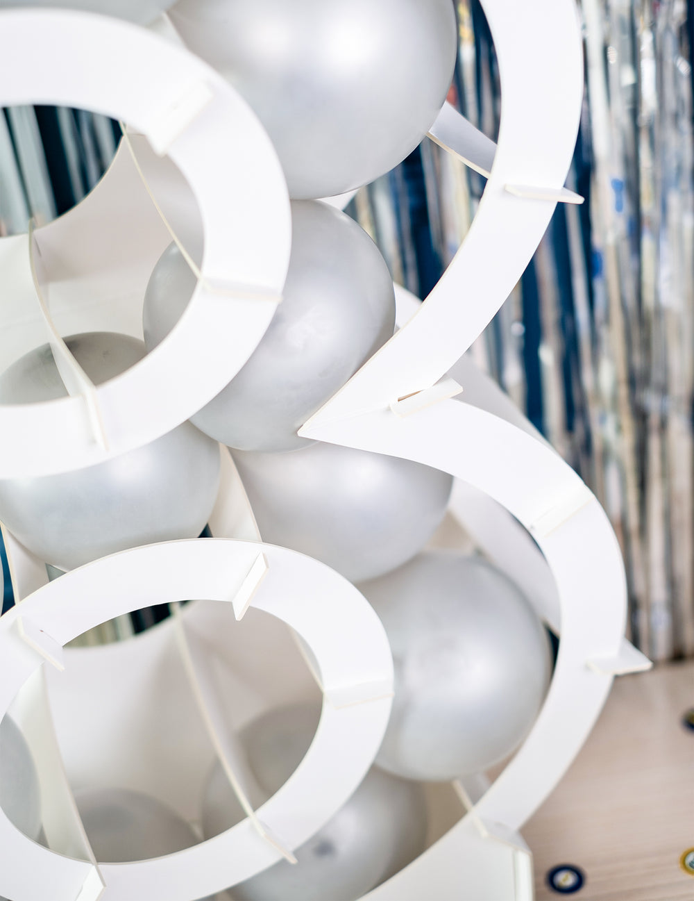 Zoom sur le garnissage de ballons de la structure chiffre pour décoration de fête blanc en carton à garnir