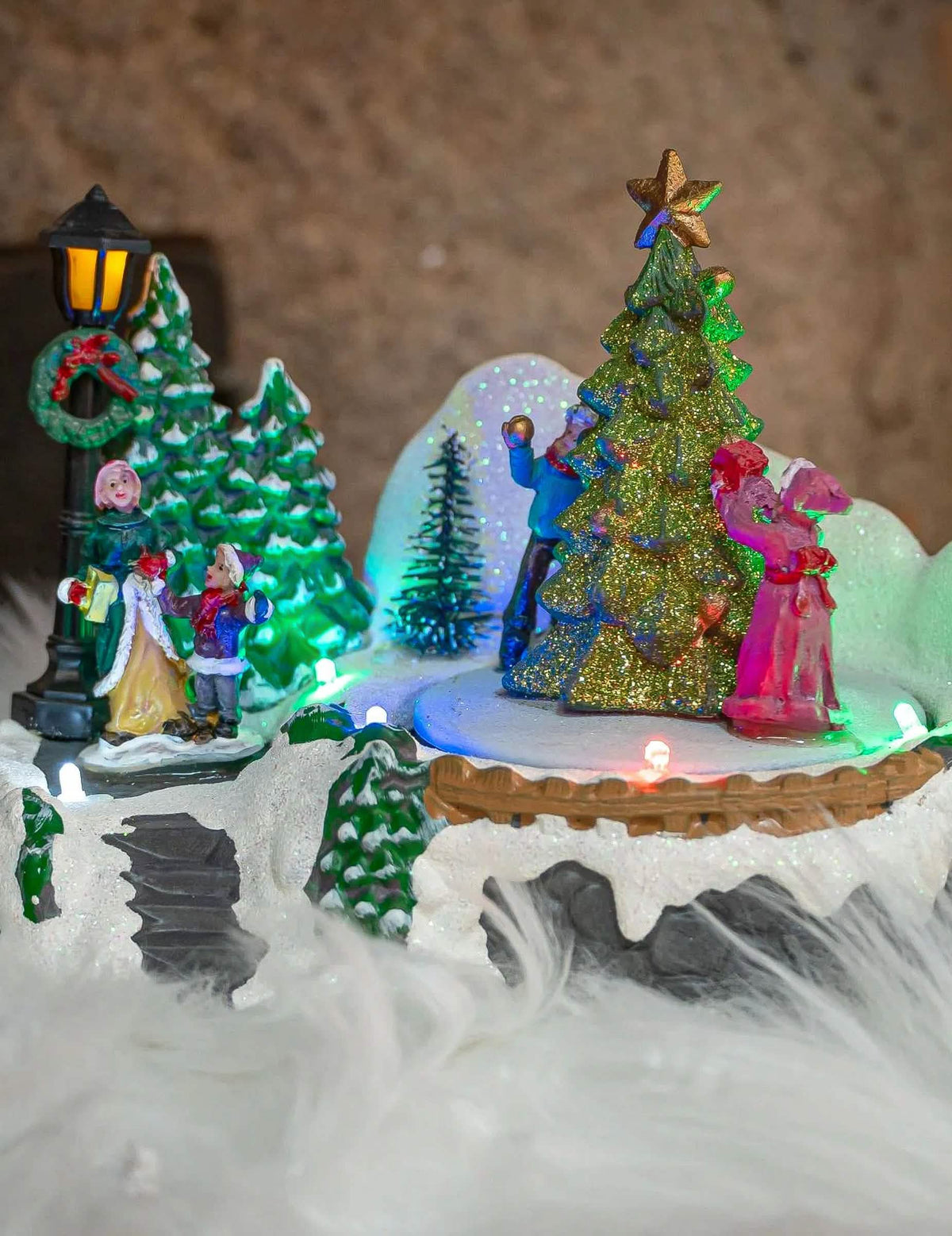 Detalhe das figuras e da árvore de natal com purpurinas da Aldeia de natal luminosa árvore
